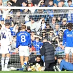 Petugas medis memberikan perawatan kepada kiper yang terbaring di lapangan