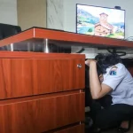 Seorang ASN berlindung di bawah meja saat simulasi gempa bumi di Jakarta Selatan