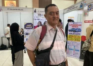 Seorang pria paruh baya sedang melihat informasi lowongan pekerjaan di bursa kerja